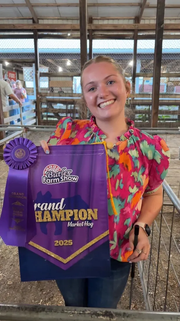 Exhibitor smiling with her Grand Champion banner and rosette